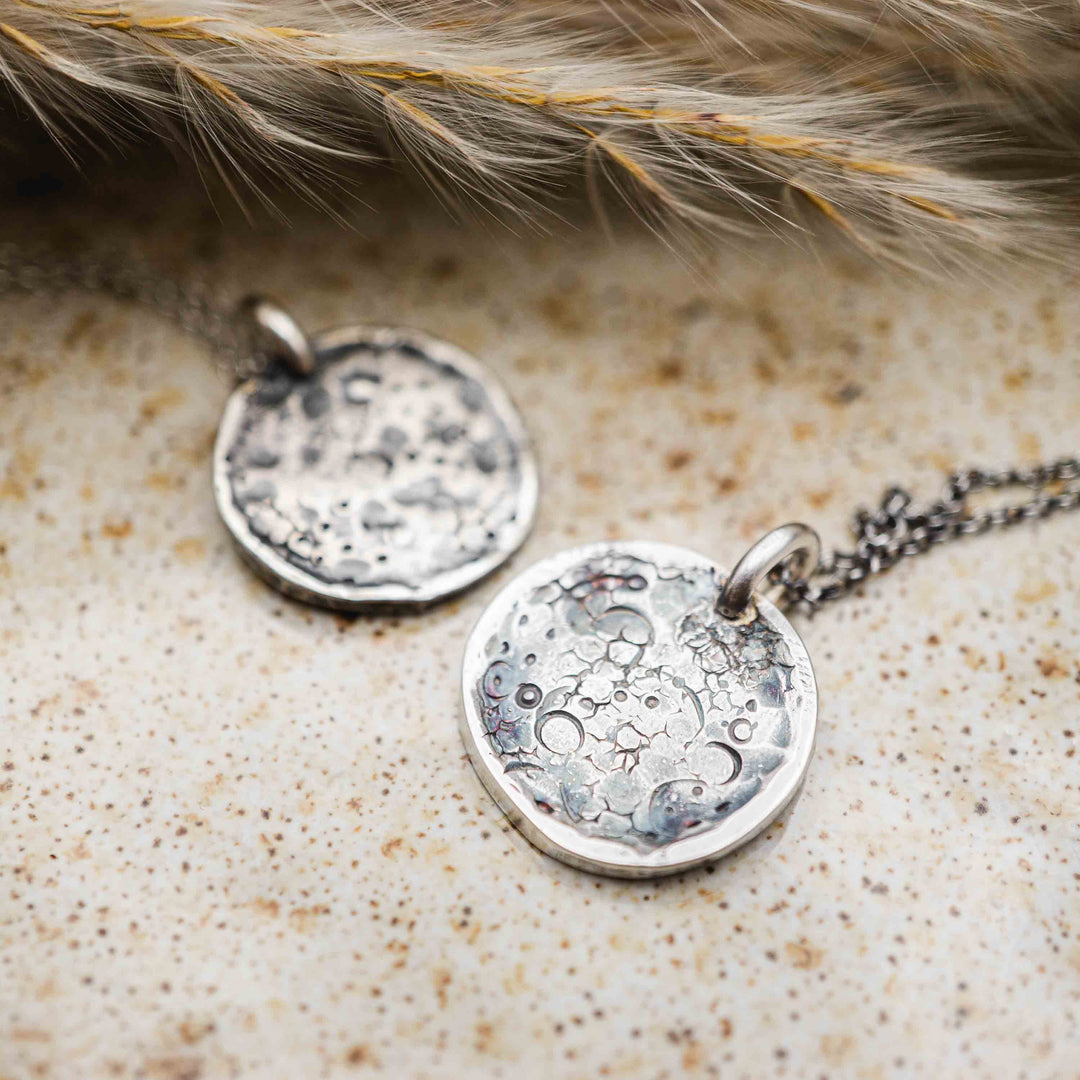 Detailaufnahme von runden Mond-Ketten aus Sterling Silber 925 mit handpunzierter Gravur und organischer Struktur.
