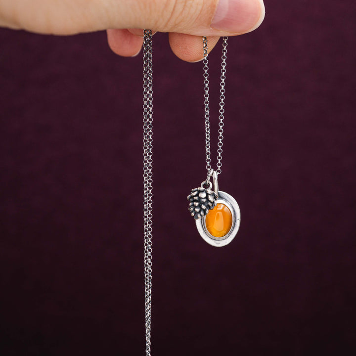 Herbstschmuck bestehend aus einer zarten Silberkette mit kleinem Tannenzapfen Anhänger und rotem Karneol, eingefasst in Sterling Silber 925.