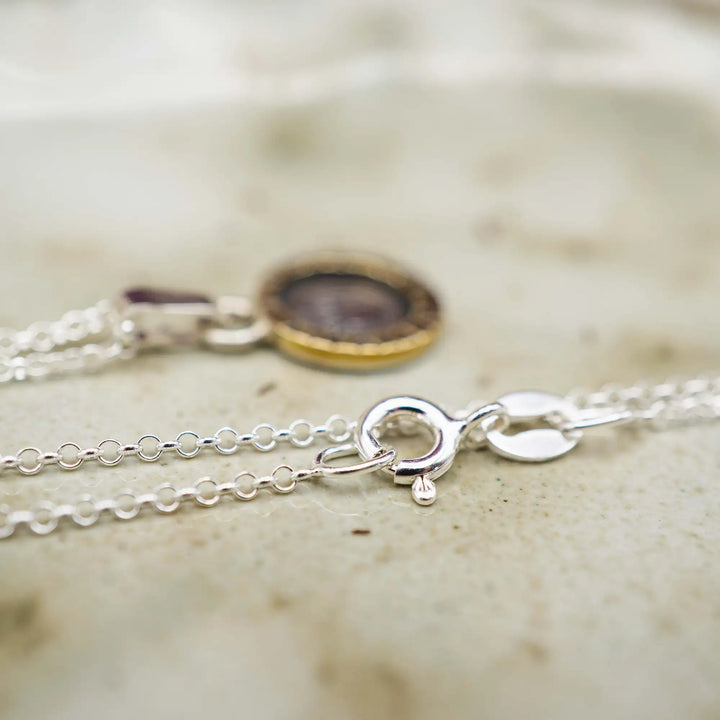 Eine kurze Silberkette aus Sterling Silber 925 mit einem kleinen gravierten Eichel Anhänger, eingerahmt von einem goldenem Rahmen.