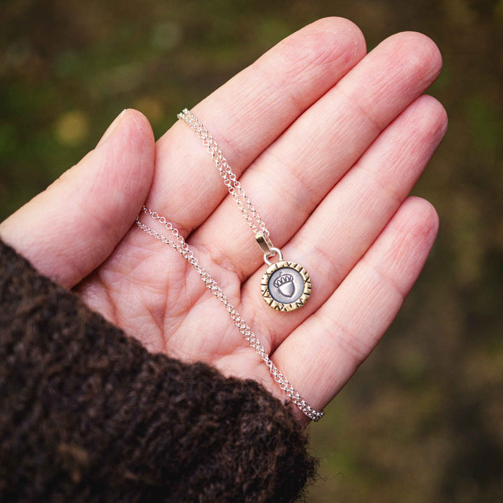 Eine kurze Silberkette aus Sterling Silber 925 mit einem kleinen gravierten Eichel Anhänger, eingerahmt von einem goldenem Rahmen.