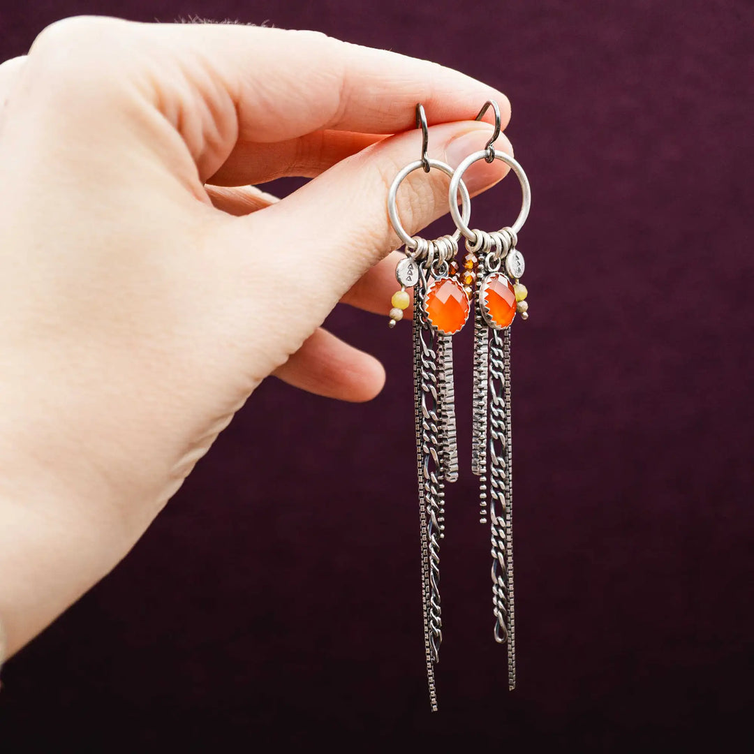 Lange Ohrringe aus Silber mit Quasten und Fransen aus Ketten. Die Ohrhänger tragen mehrere Edelstein Charms, unter anderem einen roten, facettierten Karneol.