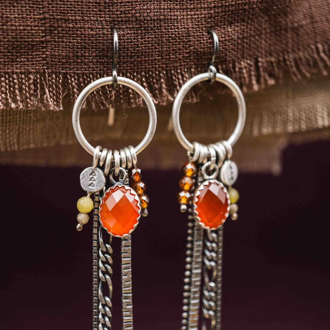 Lange Ohrringe aus Silber mit Quasten und Fransen aus Ketten. Die Ohrhänger tragen mehrere Edelstein Charms, unter anderem einen roten, facettierten Karneol.