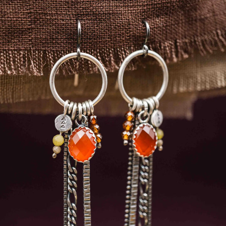 Lange Ohrringe aus Silber mit Quasten und Fransen aus Ketten. Die Ohrhänger tragen mehrere Edelstein Charms, unter anderem einen roten, facettierten Karneol.