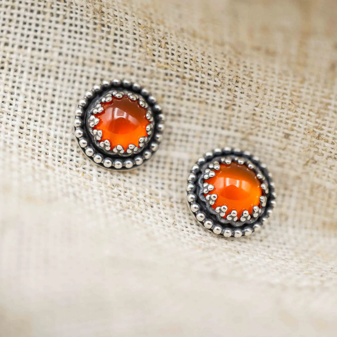 Handgefertigte Karneol Ohrstecker aus Sterling Silber 925 mit rundem Edelstein. Der leuchtend rote Karneol sitzt in einer patinierten Krone aus Silberspitze. Die kleinen Ohrstecker aus Silber sind minimalistischer Edelstein Schmuck, perfekt für Alltag und als Schmuck Geschenkidee für Frauen.