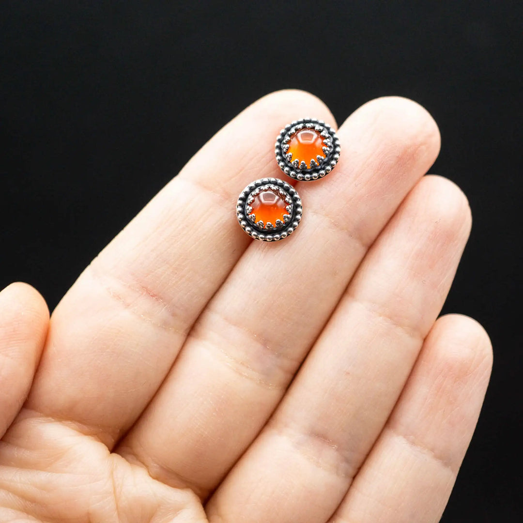 Handgefertigte Karneol Ohrstecker aus Sterling Silber 925 mit rundem Edelstein. Der leuchtend rote Karneol sitzt in einer patinierten Krone aus Silberspitze. Die kleinen Ohrstecker aus Silber sind minimalistischer Edelstein Schmuck, perfekt für Alltag und als Schmuck Geschenkidee für Frauen.