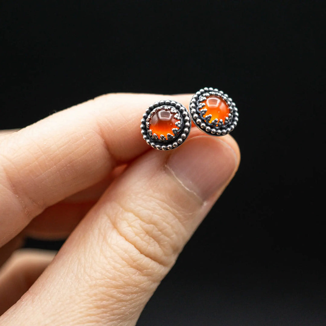 Handgefertigte Karneol Ohrstecker aus Sterling Silber 925 mit rundem Edelstein. Der leuchtend rote Karneol sitzt in einer patinierten Krone aus Silberspitze. Die kleinen Ohrstecker aus Silber sind minimalistischer Edelstein Schmuck, perfekt für Alltag und als Schmuck Geschenkidee für Frauen.