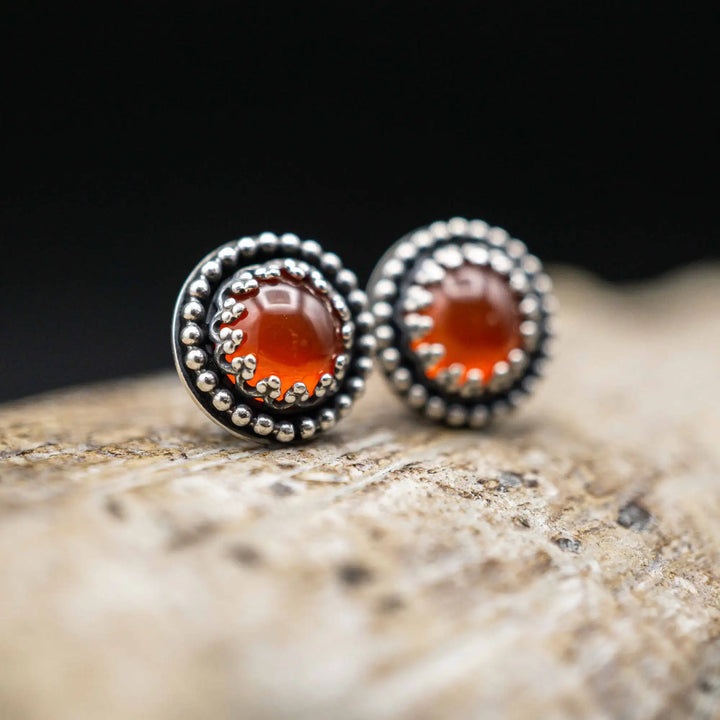 Handgefertigte Karneol Ohrstecker aus Sterling Silber 925 mit rundem Edelstein. Der leuchtend rote Karneol sitzt in einer patinierten Krone aus Silberspitze. Die kleinen Ohrstecker aus Silber sind minimalistischer Edelstein Schmuck, perfekt für Alltag und als Schmuck Geschenkidee für Frauen.