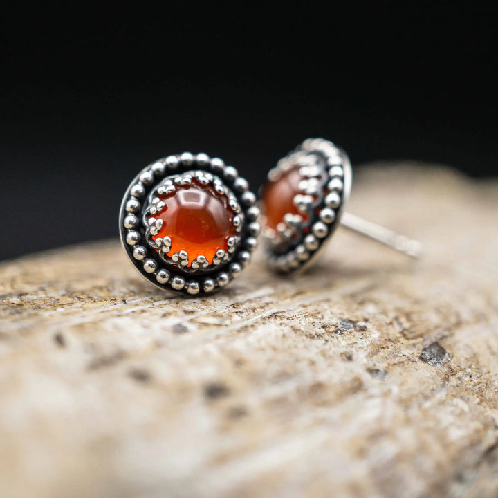 Handgefertigte Karneol Ohrstecker aus Sterling Silber 925 mit rundem Edelstein. Der leuchtend rote Karneol sitzt in einer patinierten Krone aus Silberspitze. Die kleinen Ohrstecker aus Silber sind minimalistischer Edelstein Schmuck, perfekt für Alltag und als Schmuck Geschenkidee für Frauen.