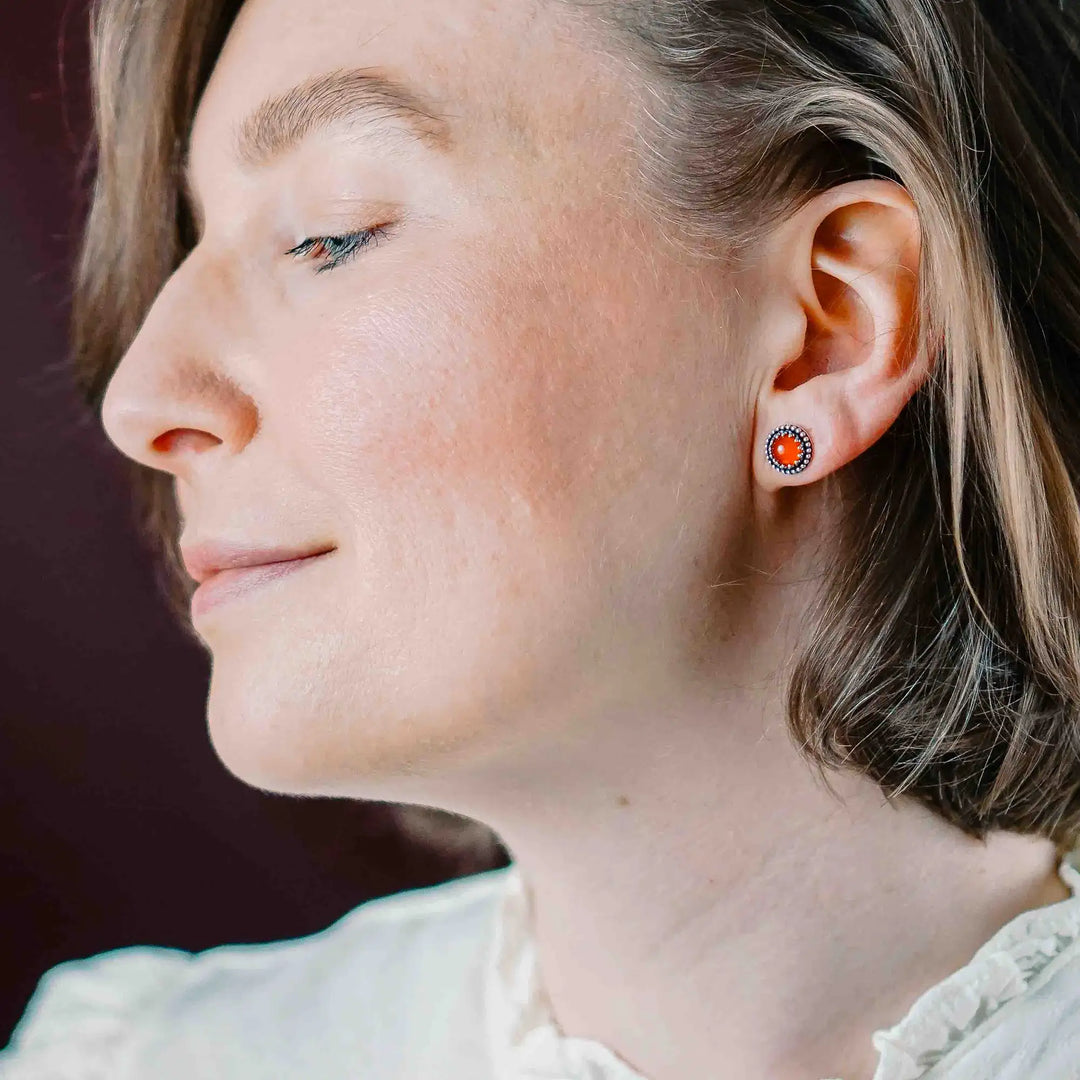 Handgefertigte Karneol Ohrstecker aus Sterling Silber 925 mit rundem Edelstein. Der leuchtend rote Karneol sitzt in einer patinierten Krone aus Silberspitze. Die kleinen Ohrstecker aus Silber sind minimalistischer Edelstein Schmuck, perfekt für Alltag und als Schmuck Geschenkidee für Frauen.