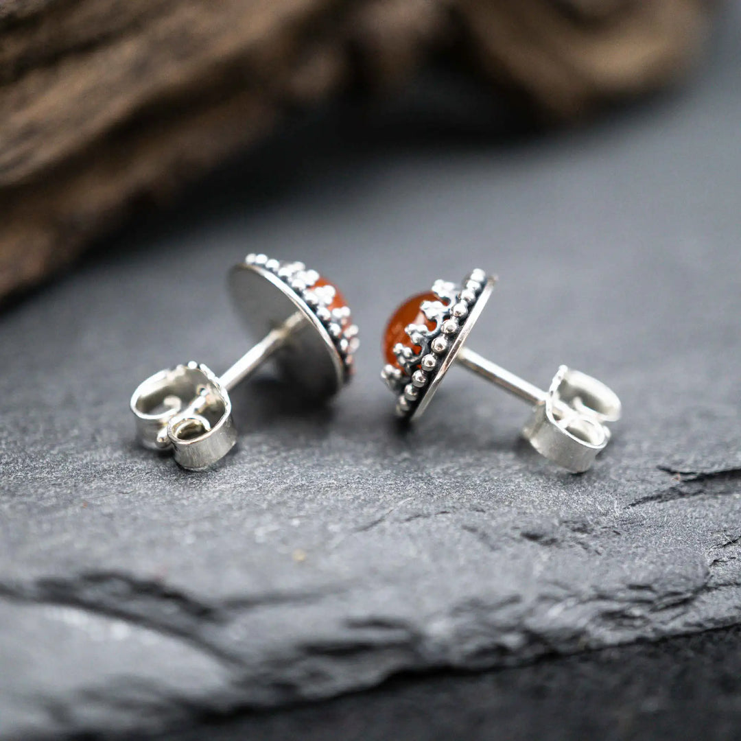 Handgefertigte Karneol Ohrstecker aus Sterling Silber 925 mit rundem Edelstein. Der leuchtend rote Karneol sitzt in einer patinierten Krone aus Silberspitze. Die kleinen Ohrstecker aus Silber sind minimalistischer Edelstein Schmuck, perfekt für Alltag und als Schmuck Geschenkidee für Frauen.
