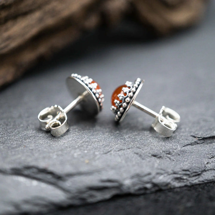 Handgefertigte Karneol Ohrstecker aus Sterling Silber 925 mit rundem Edelstein. Der leuchtend rote Karneol sitzt in einer patinierten Krone aus Silberspitze. Die kleinen Ohrstecker aus Silber sind minimalistischer Edelstein Schmuck, perfekt für Alltag und als Schmuck Geschenkidee für Frauen.