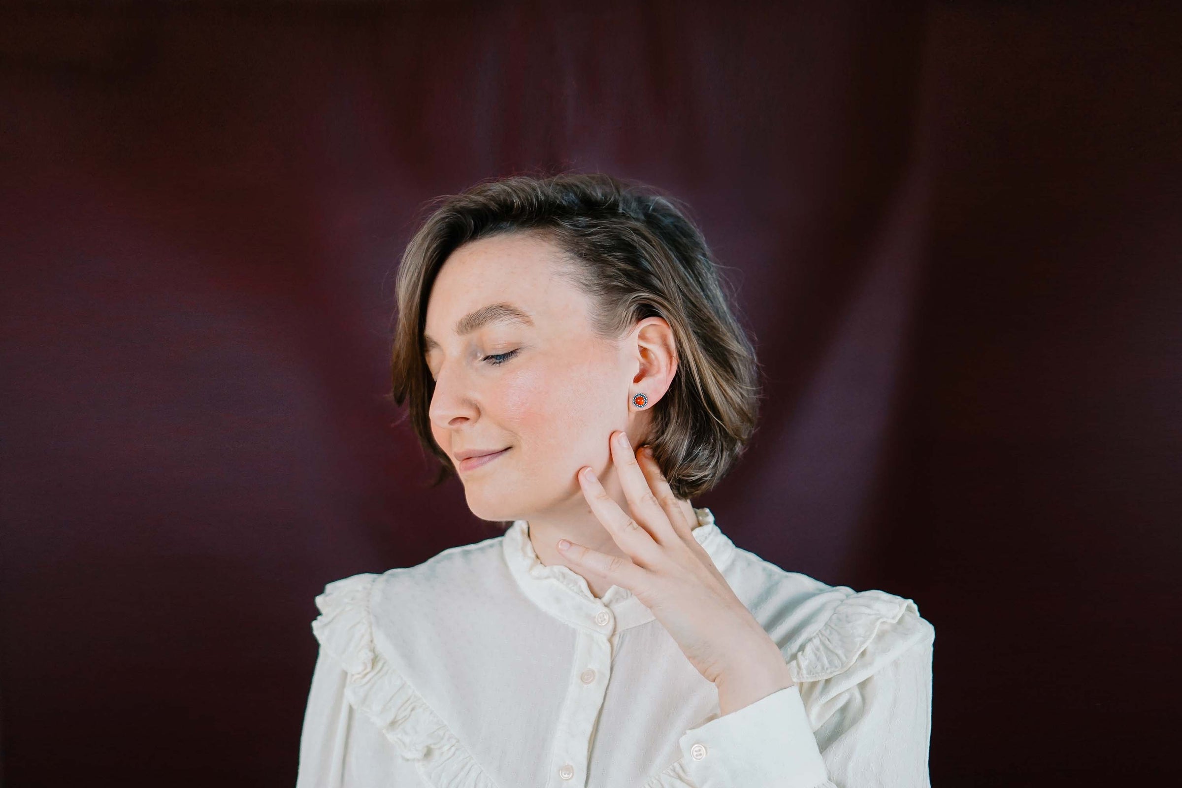 Handgefertigte Karneol Ohrstecker aus Sterling Silber 925 mit rundem Edelstein. Der leuchtend rote Karneol sitzt in einer patinierten Krone aus Silberspitze. Die kleinen Ohrstecker aus Silber sind minimalistischer Edelstein Schmuck, perfekt für Alltag und als Schmuck Geschenkidee für Frauen.