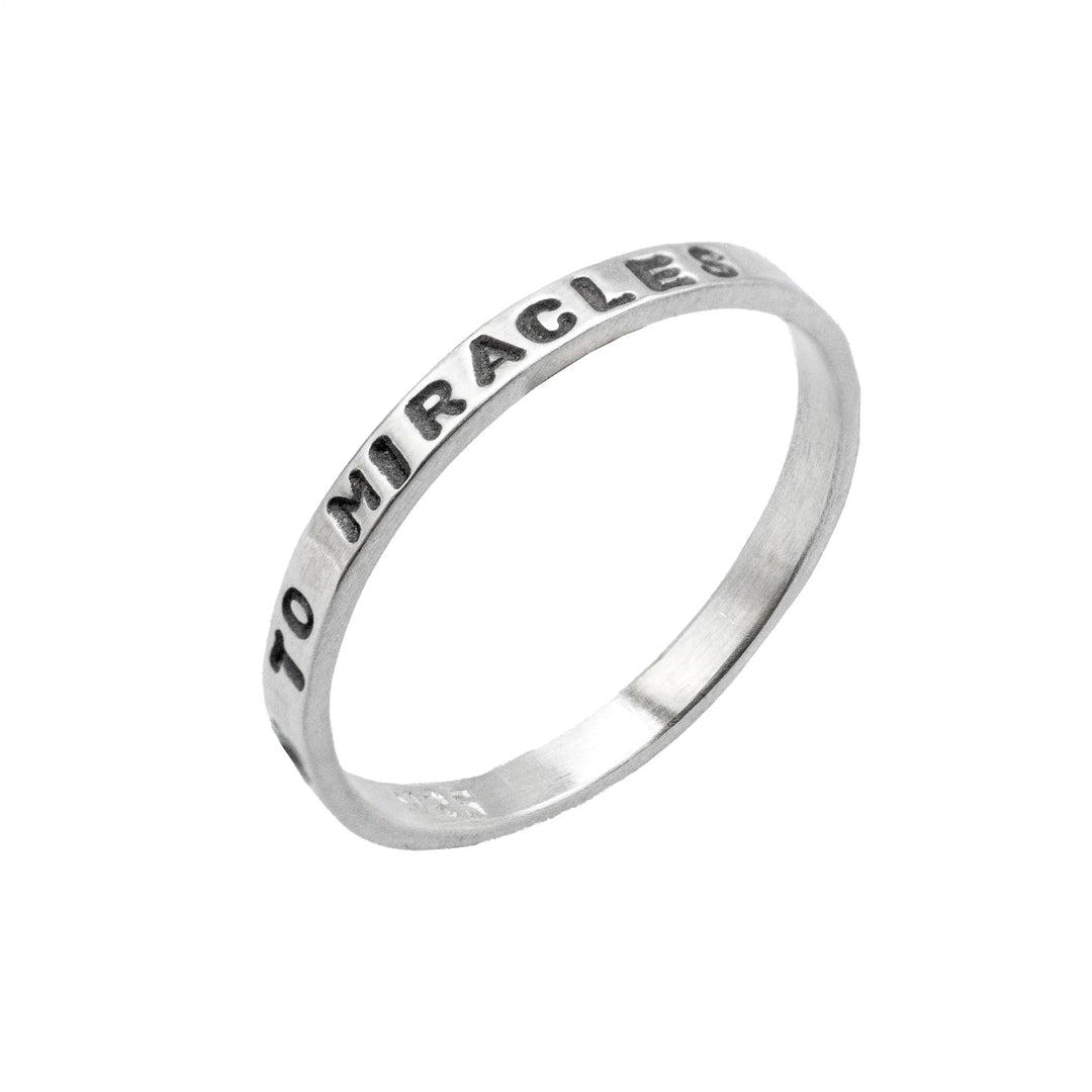 Schmaler Ring mit personalisierter Gravur aus Sterling Silber 925. In den dünnen Silberring sind Buchstaben und Texturen gehämmert nach individuellem Wunsch der Kundin. Auf einem Ring ist der Text “Open to Miracles” zu lesen, auf einem anderen ist der Spruch “A little bit of Madness is Key” eingraviert. Den dritten silbernen Ring zieren die Worte “Mädel, machs für dich”.