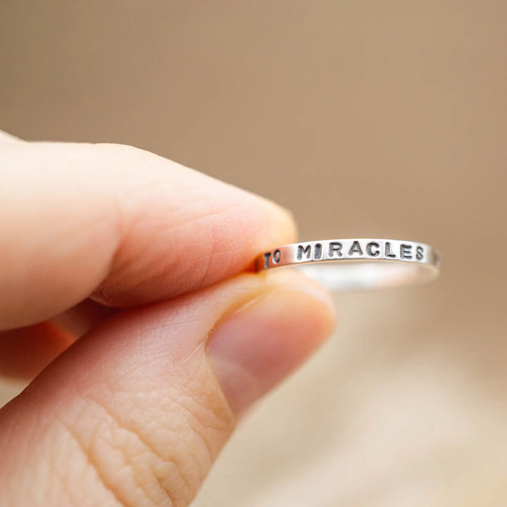 Schmaler Ring mit personalisierter Gravur aus Sterling Silber 925. In den dünnen Silberring sind Buchstaben und Texturen gehämmert nach individuellem Wunsch der Kundin. Auf einem Ring ist der Text “Open to Miracles” zu lesen, auf einem anderen ist der Spruch “A little bit of Madness is Key” eingraviert. Den dritten silbernen Ring zieren die Worte “Mädel, machs für dich”.