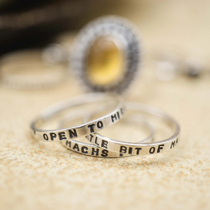 Schmaler Ring mit personalisierter Gravur aus Sterling Silber 925. In den dünnen Silberring sind Buchstaben und Texturen gehämmert nach individuellem Wunsch der Kundin. Auf einem Ring ist der Text “Open to Miracles” zu lesen, auf einem anderen ist der Spruch “A little bit of Madness is Key” eingraviert. Den dritten silbernen Ring zieren die Worte “Mädel, machs für dich”.