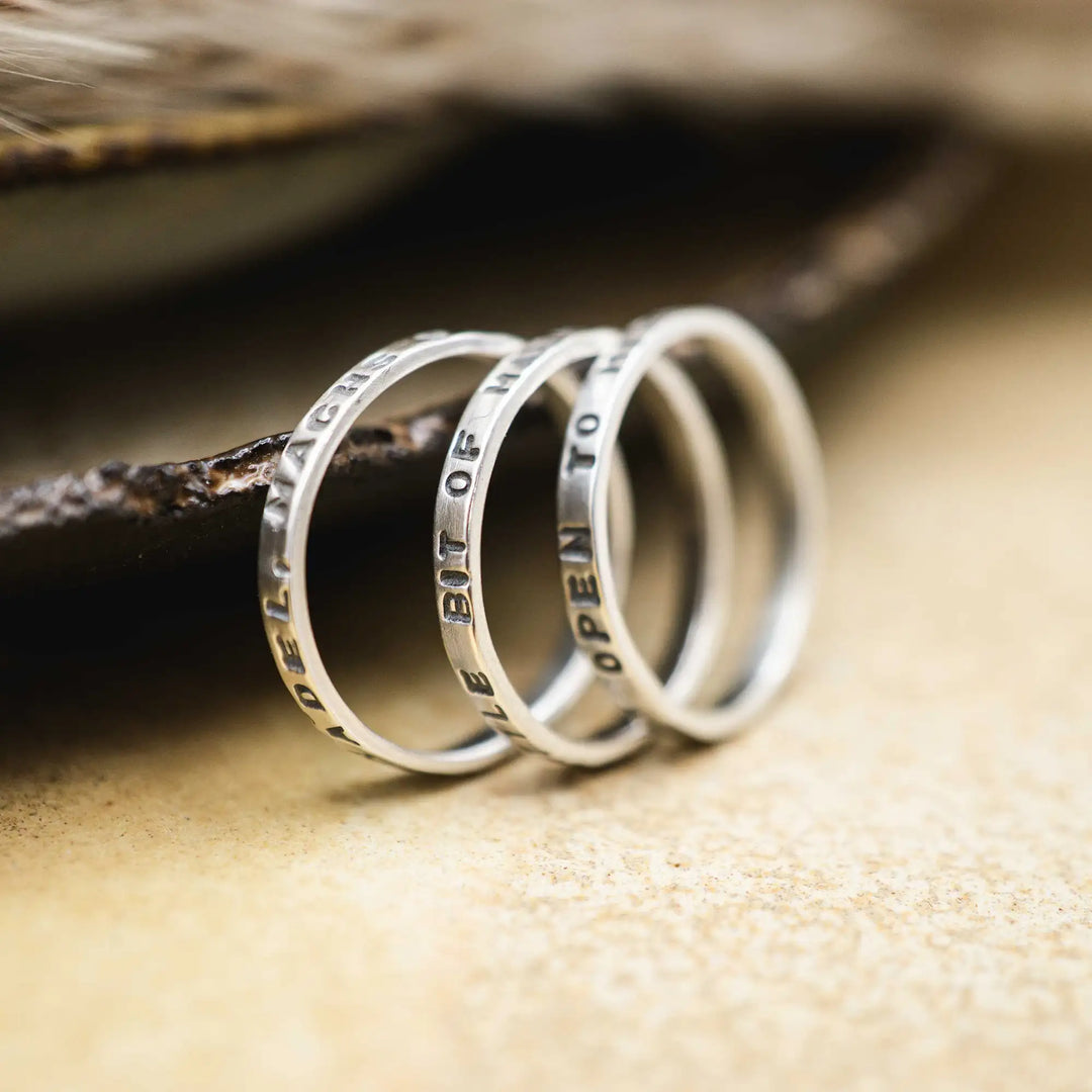 Schmaler Ring mit personalisierter Gravur aus Sterling Silber 925. In den dünnen Silberring sind Buchstaben und Texturen gehämmert nach individuellem Wunsch der Kundin. Auf einem Ring ist der Text “Open to Miracles” zu lesen, auf einem anderen ist der Spruch “A little bit of Madness is Key” eingraviert. Den dritten silbernen Ring zieren die Worte “Mädel, machs für dich”.