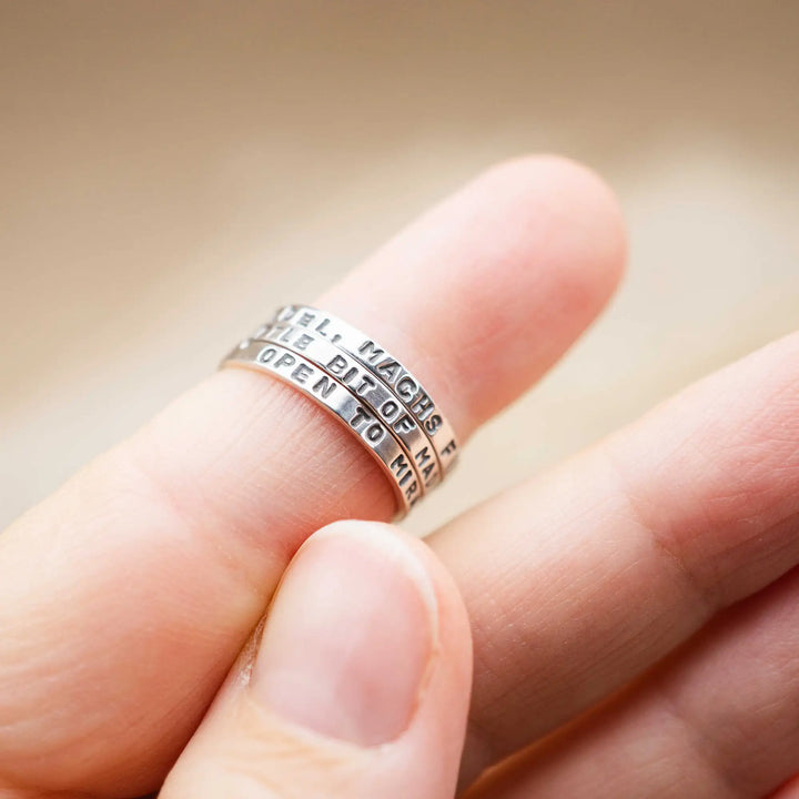 Schmaler Ring mit personalisierter Gravur aus Sterling Silber 925. In den dünnen Silberring sind Buchstaben und Texturen gehämmert nach individuellem Wunsch der Kundin. Auf einem Ring ist der Text “Open to Miracles” zu lesen, auf einem anderen ist der Spruch “A little bit of Madness is Key” eingraviert. Den dritten silbernen Ring zieren die Worte “Mädel, machs für dich”.