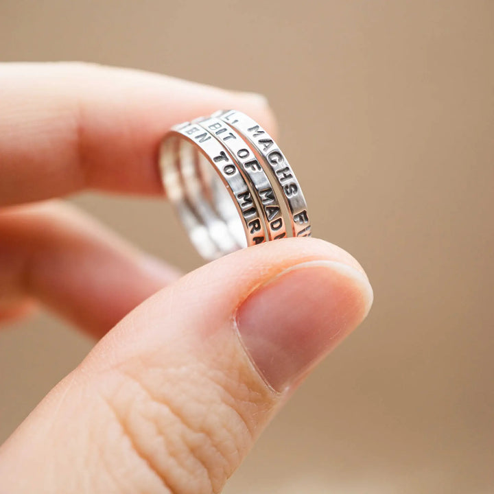 Schmaler Ring mit personalisierter Gravur aus Sterling Silber 925. In den dünnen Silberring sind Buchstaben und Texturen gehämmert nach individuellem Wunsch der Kundin. Auf einem Ring ist der Text “Open to Miracles” zu lesen, auf einem anderen ist der Spruch “A little bit of Madness is Key” eingraviert. Den dritten silbernen Ring zieren die Worte “Mädel, machs für dich”.