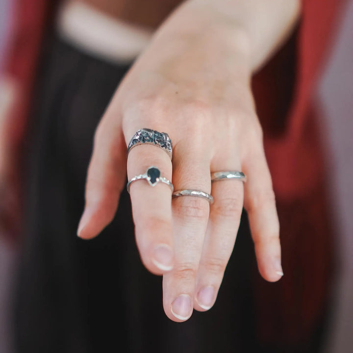 Ringe an einer Hand: Ein rustikaler Brutalist-Siegelring aus Silber, ein Ring aus Silber mit Labradorit Tropfen und zwei facettiert geschnitzte Hammerschlag Ringe aus Silber.