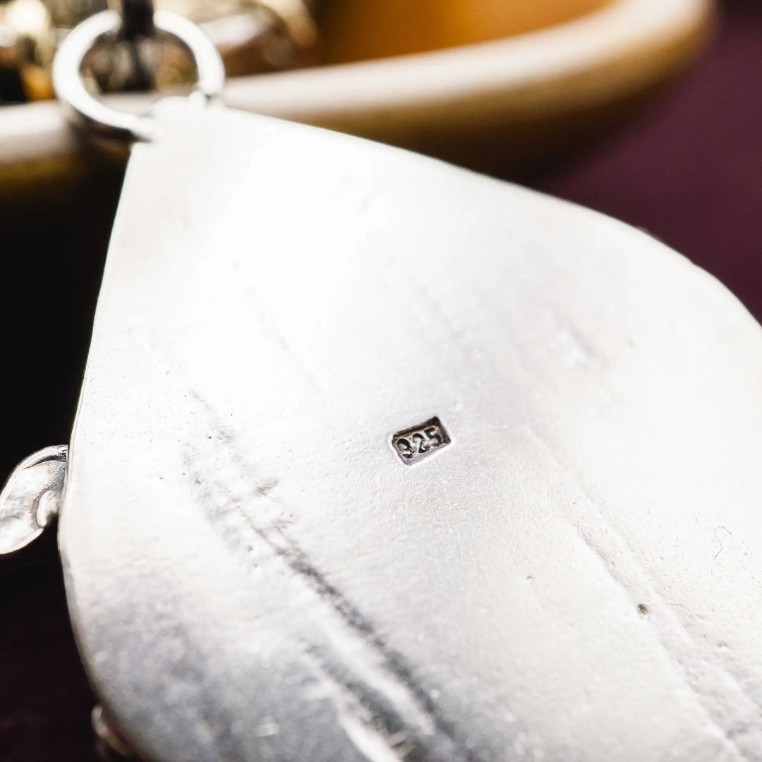 Statement Kette groß aus Silber 925. In den Anhänger eingefasst ist ein tropfenförmiger Lodolith, auch Gartenquarz genannt. Der Stein sieht aus wie eingeschlossenes grünes, gelbes und orangefarbenes Moos und ist umrandet von Pilzen, Blättern und Knospen. Ein echtes, handgefertigtes Statement Piece an Naturschmuck.
An dem Anhänger hängen außerdem 3 kleine Charms aus Messing: Ein Marienkäfer, ein Pilz und ein Blatt.